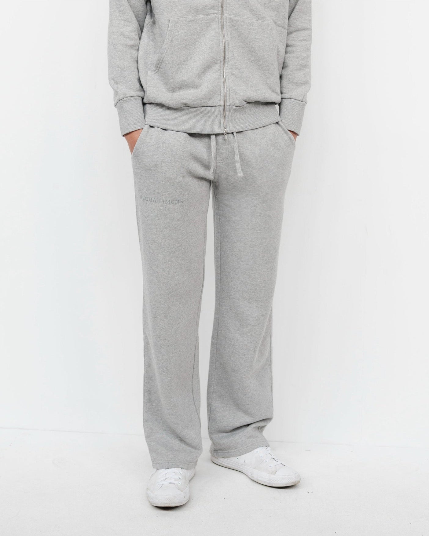 Person wearing a gray tracksuit on a white background