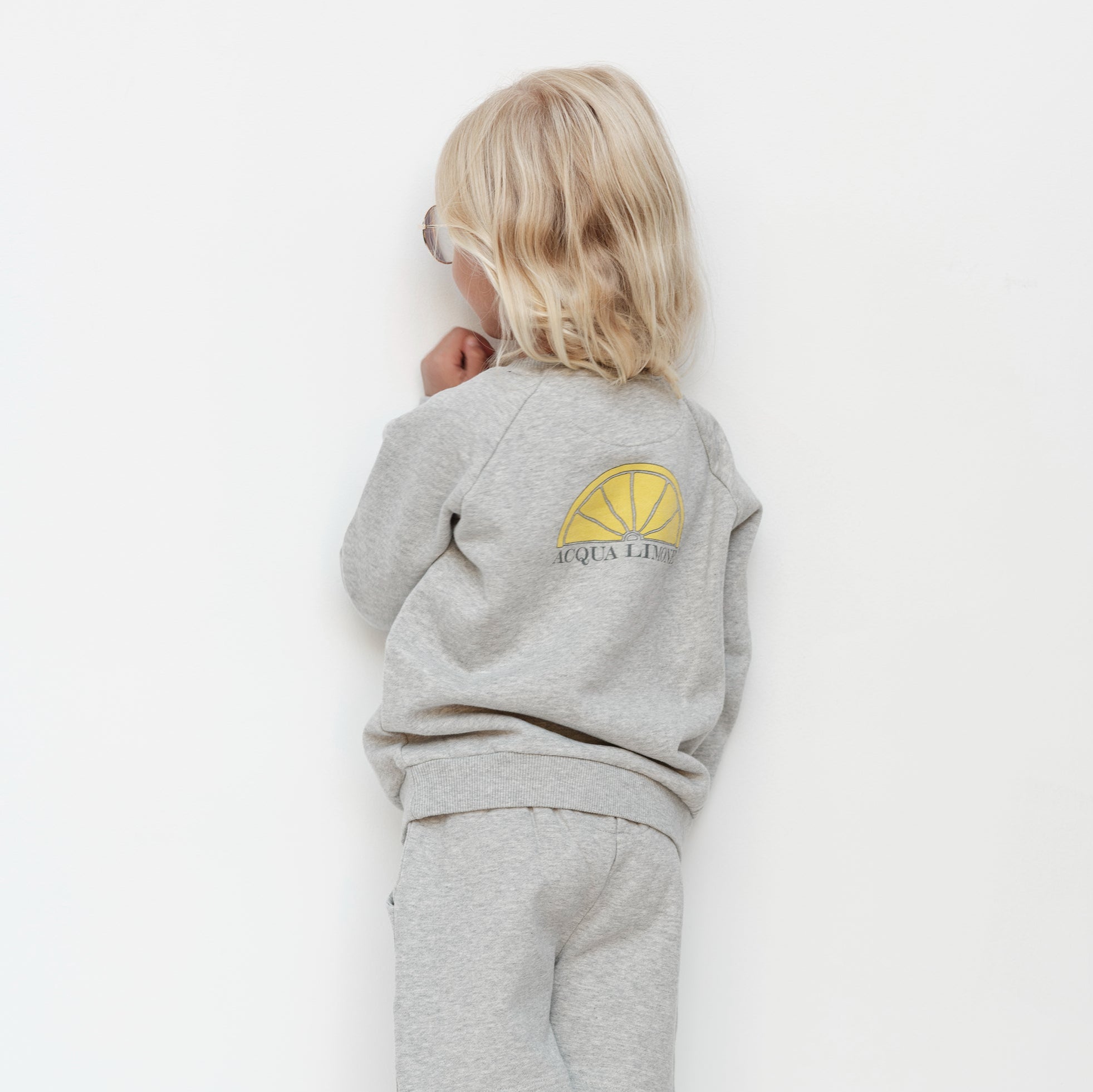 Child wearing a gray outfit with a logo on a white background