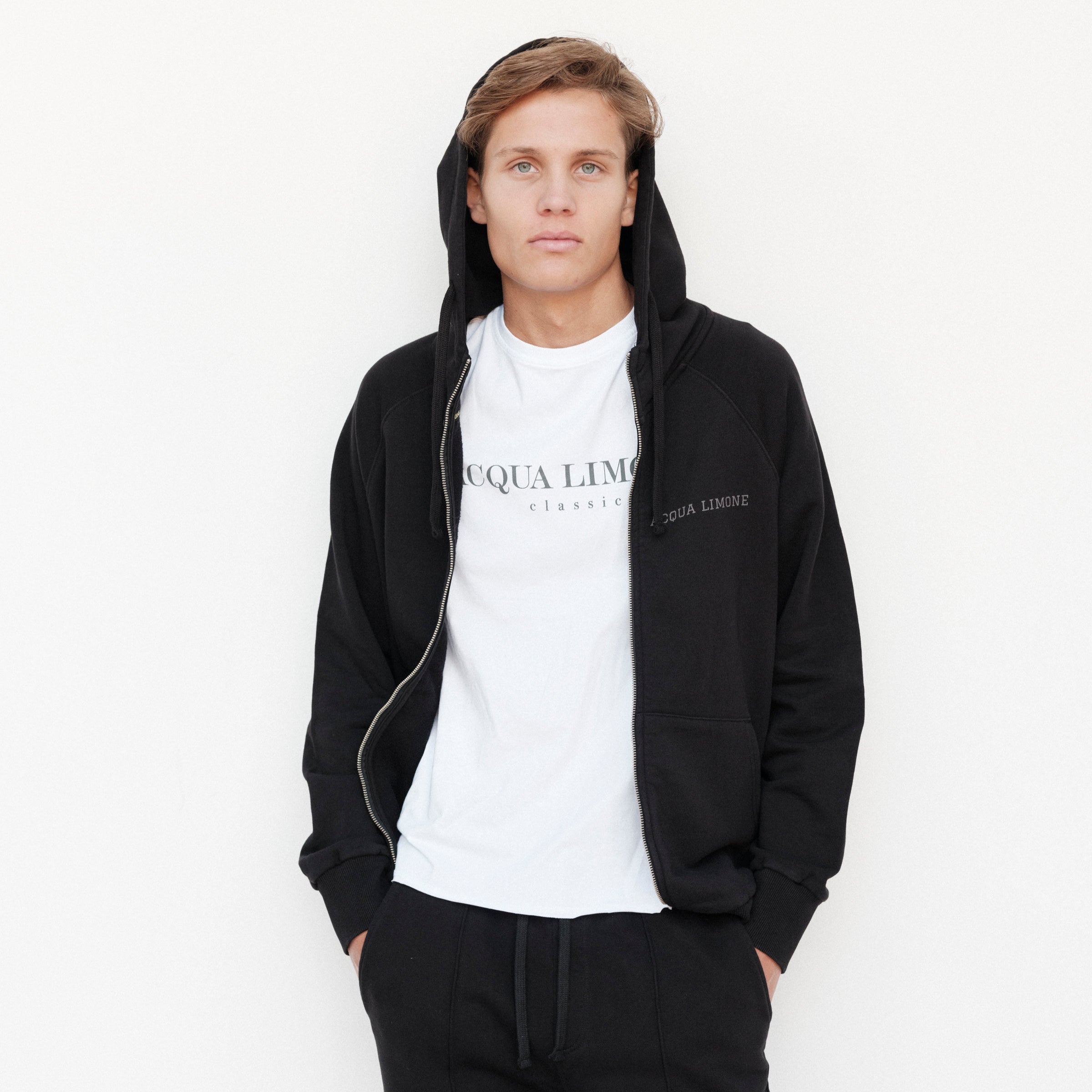 Person wearing a black hoodie and white t-shirt with 'Acqua Limone' branding on a white background