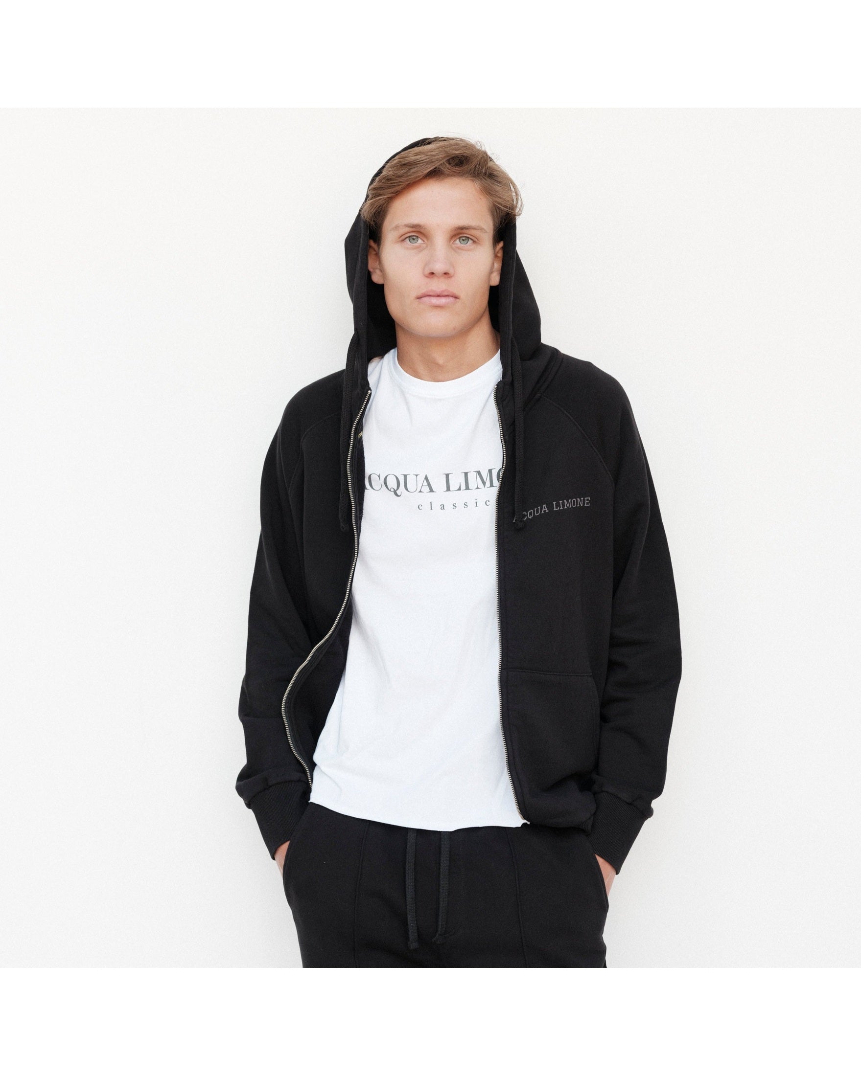 Person wearing a black hoodie and white t-shirt with 'Acqua Limone' branding on a white background