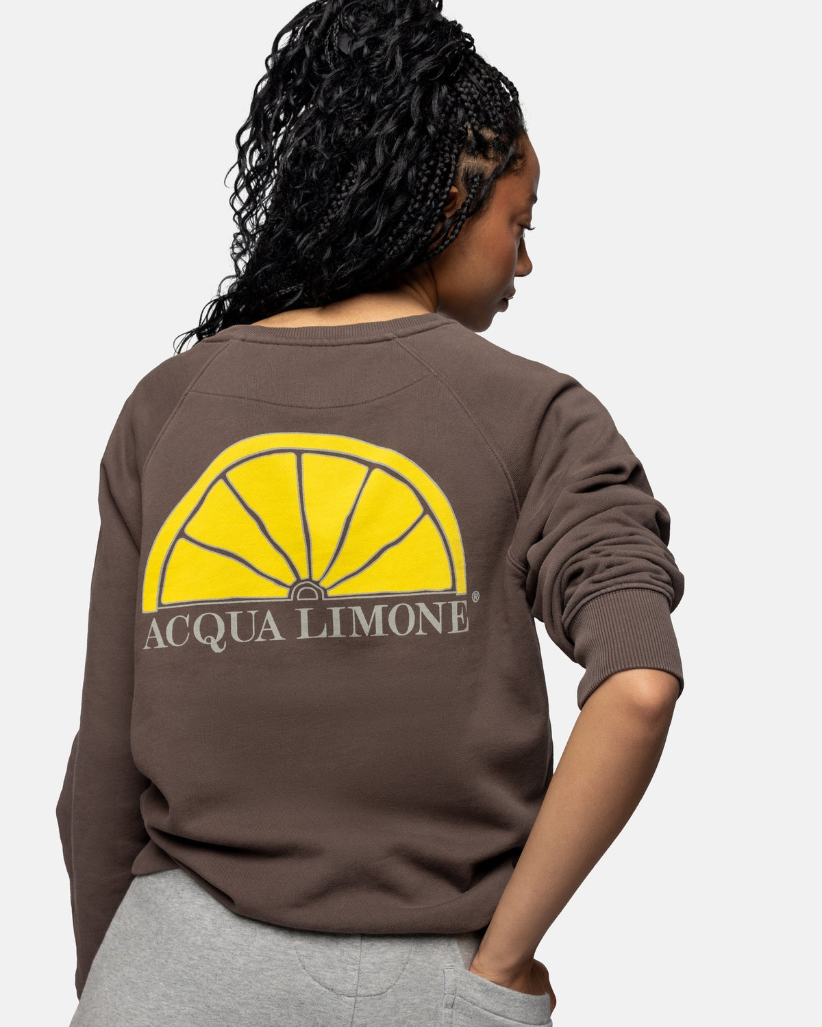 Person wearing a brown sweatshirt with Acqua Limone logo on the back