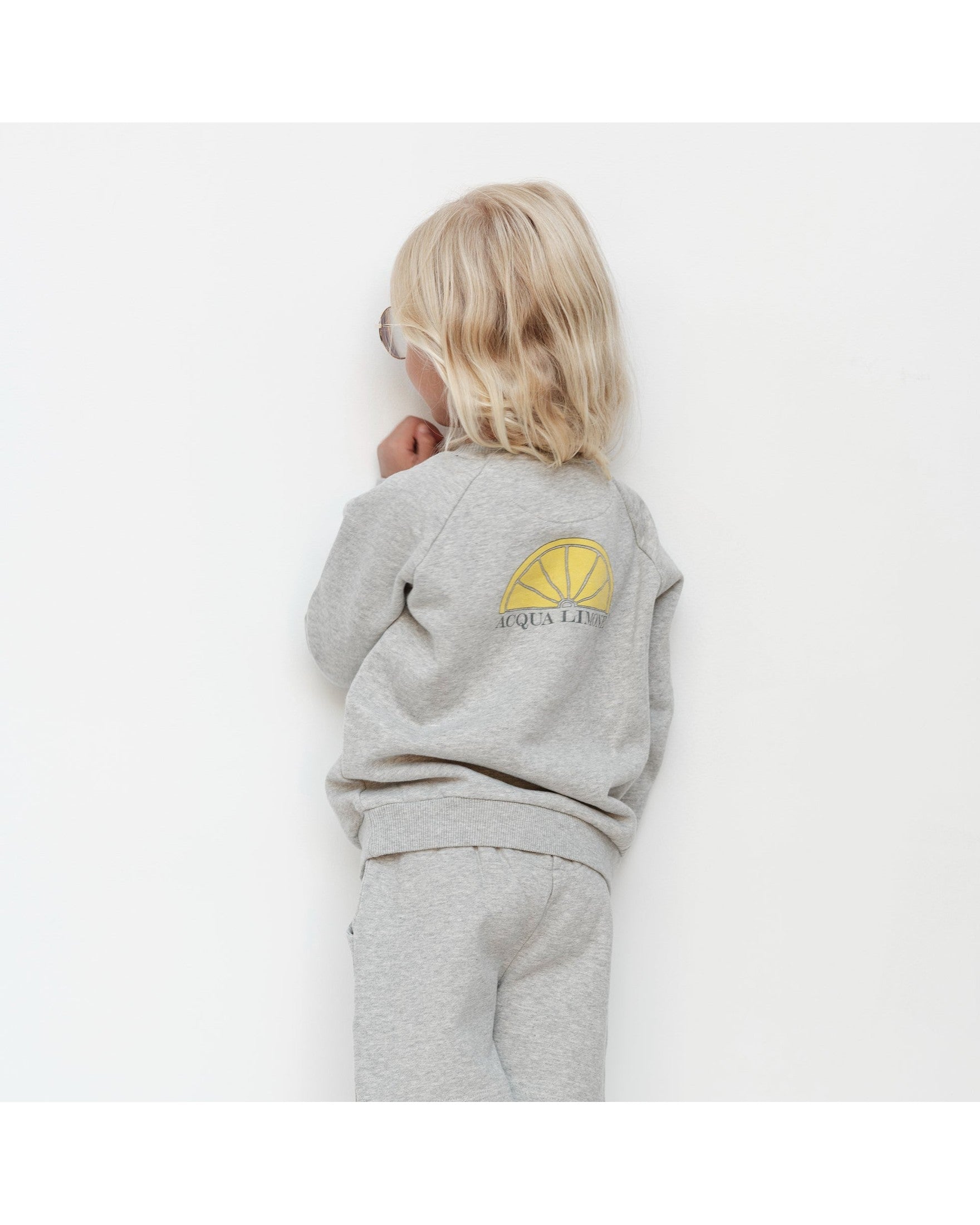 Child wearing a gray outfit with a logo on a white background