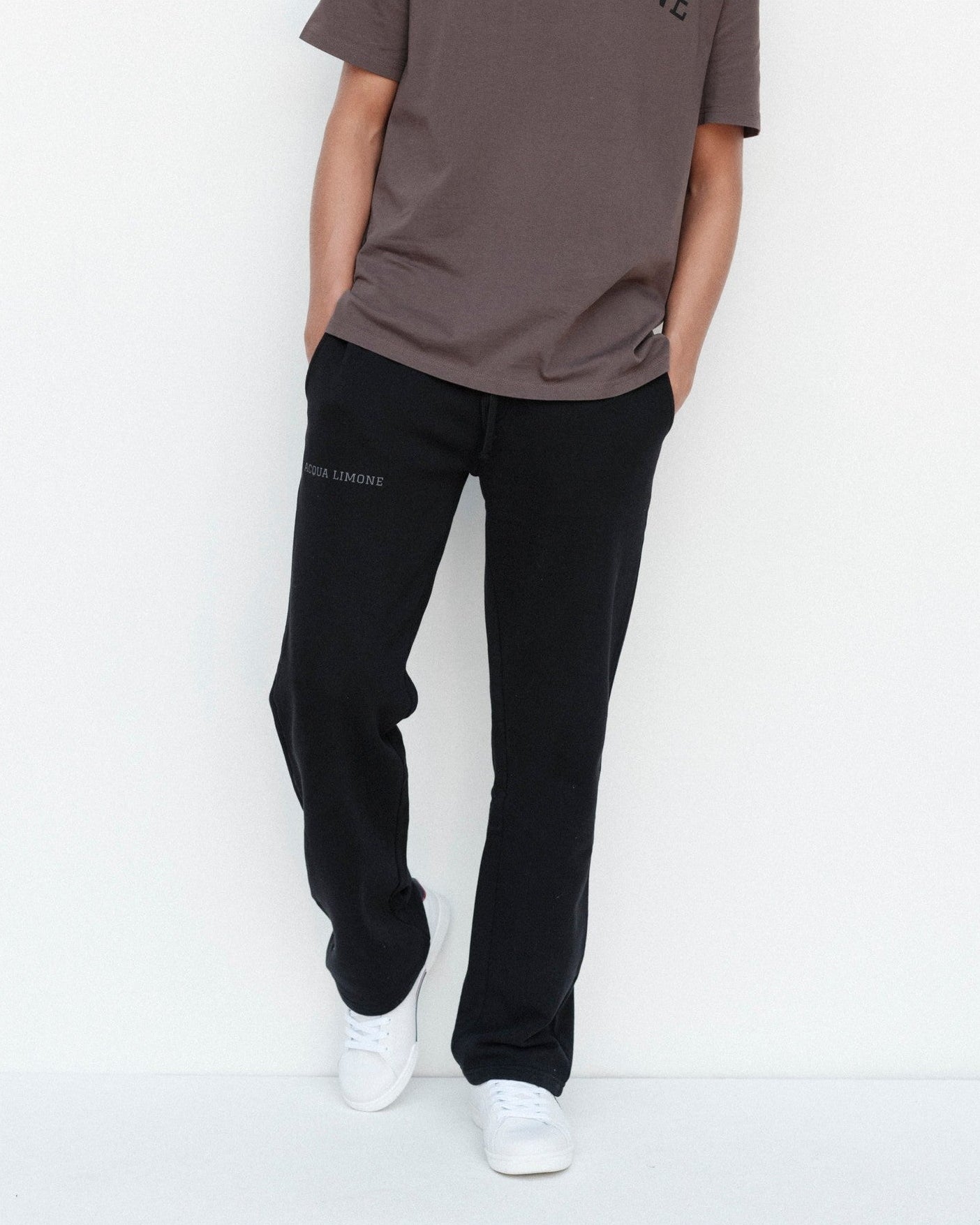 Person wearing a brown t-shirt and black pants on a white background