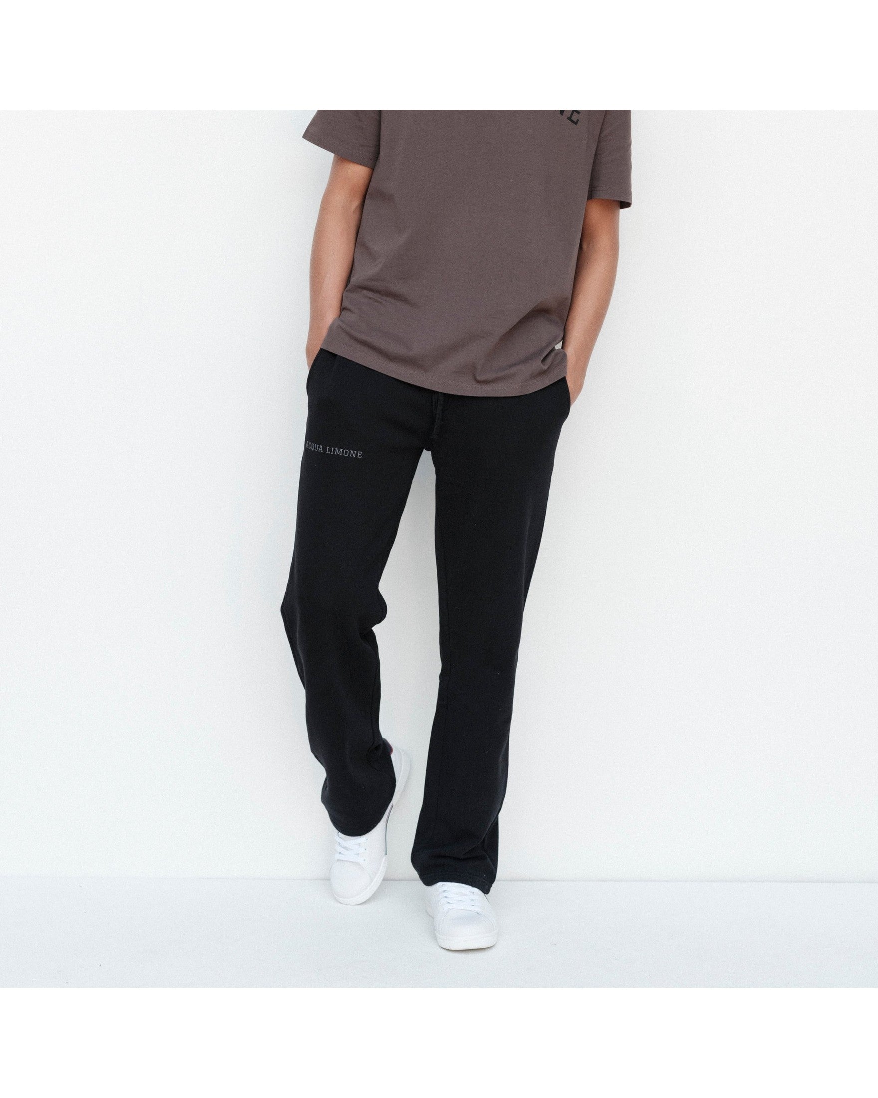 Person wearing a brown t-shirt and black pants on a white background