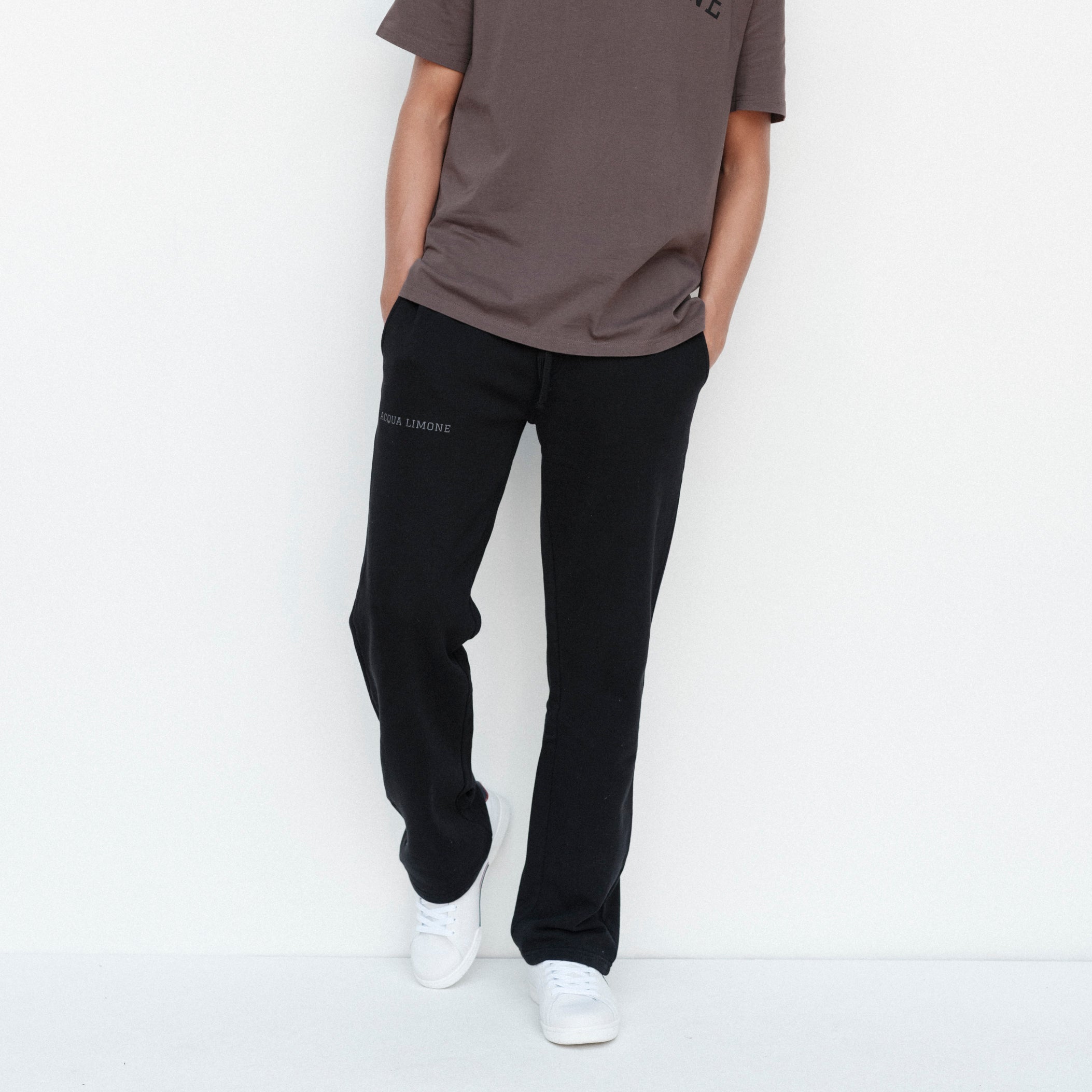 Person wearing a brown t-shirt and black pants on a white background
