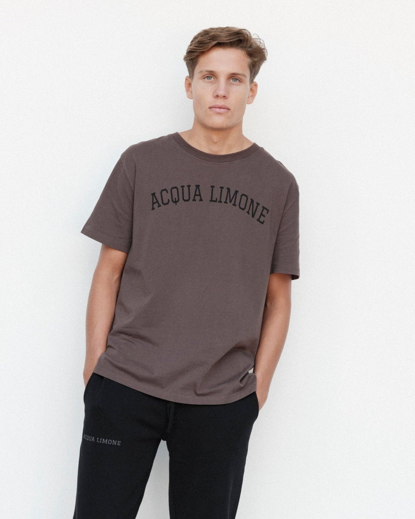 Man wearing a brown 'Acqua Limone' t-shirt against a white background