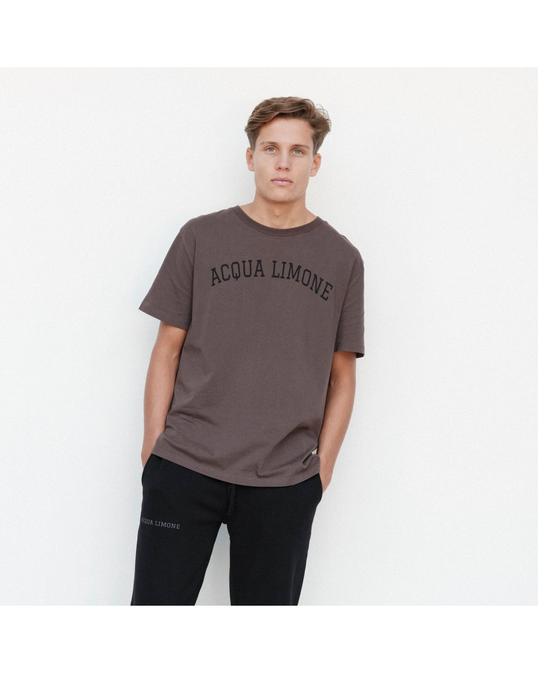 Man wearing a brown 'Acqua Limone' t-shirt against a white background