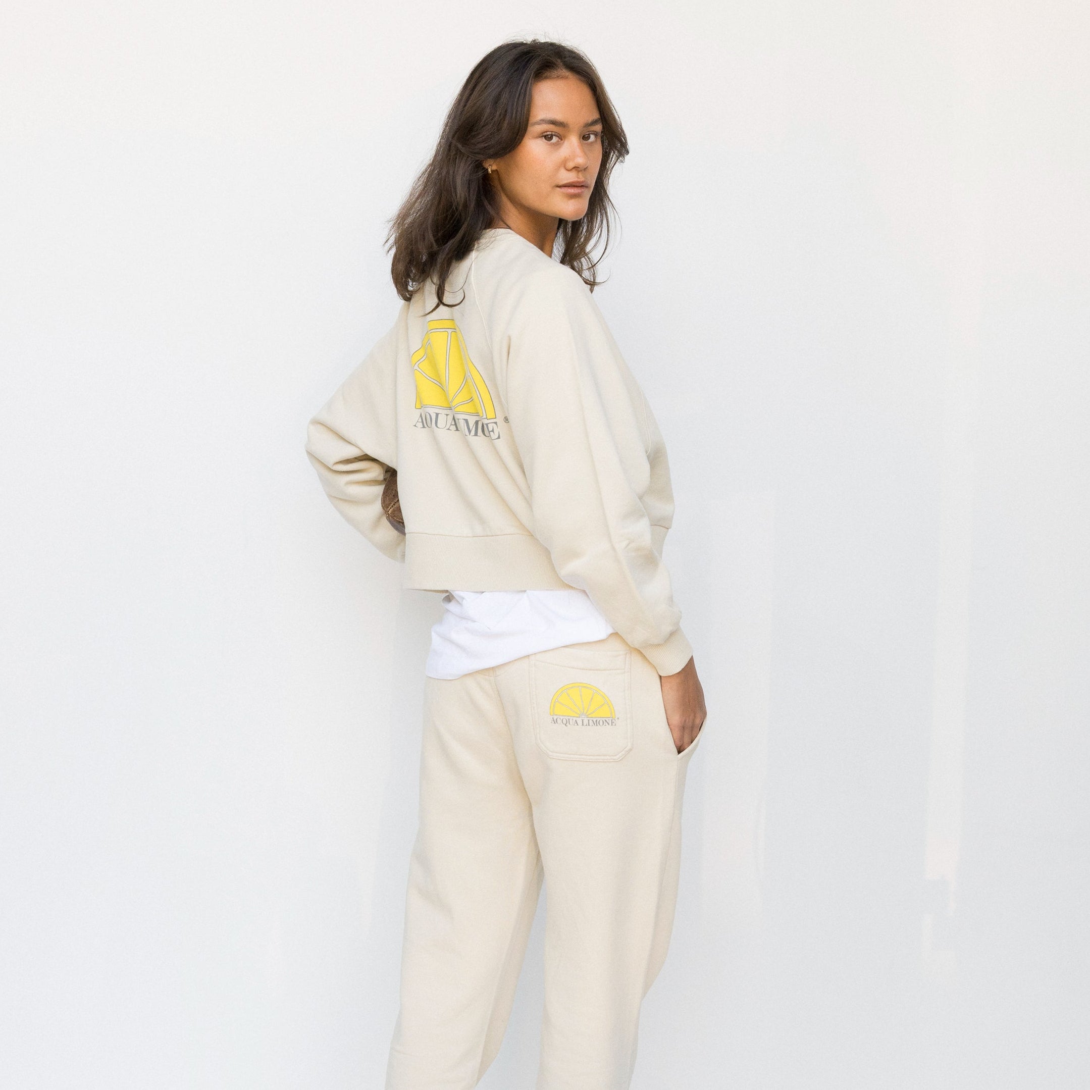 Person wearing a beige tracksuit with graphic designs on a white background